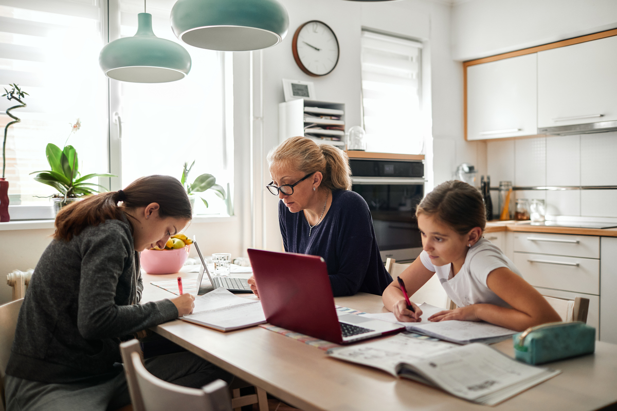 Mother helping her daughters to finish school homework during coronavirus quarantine.