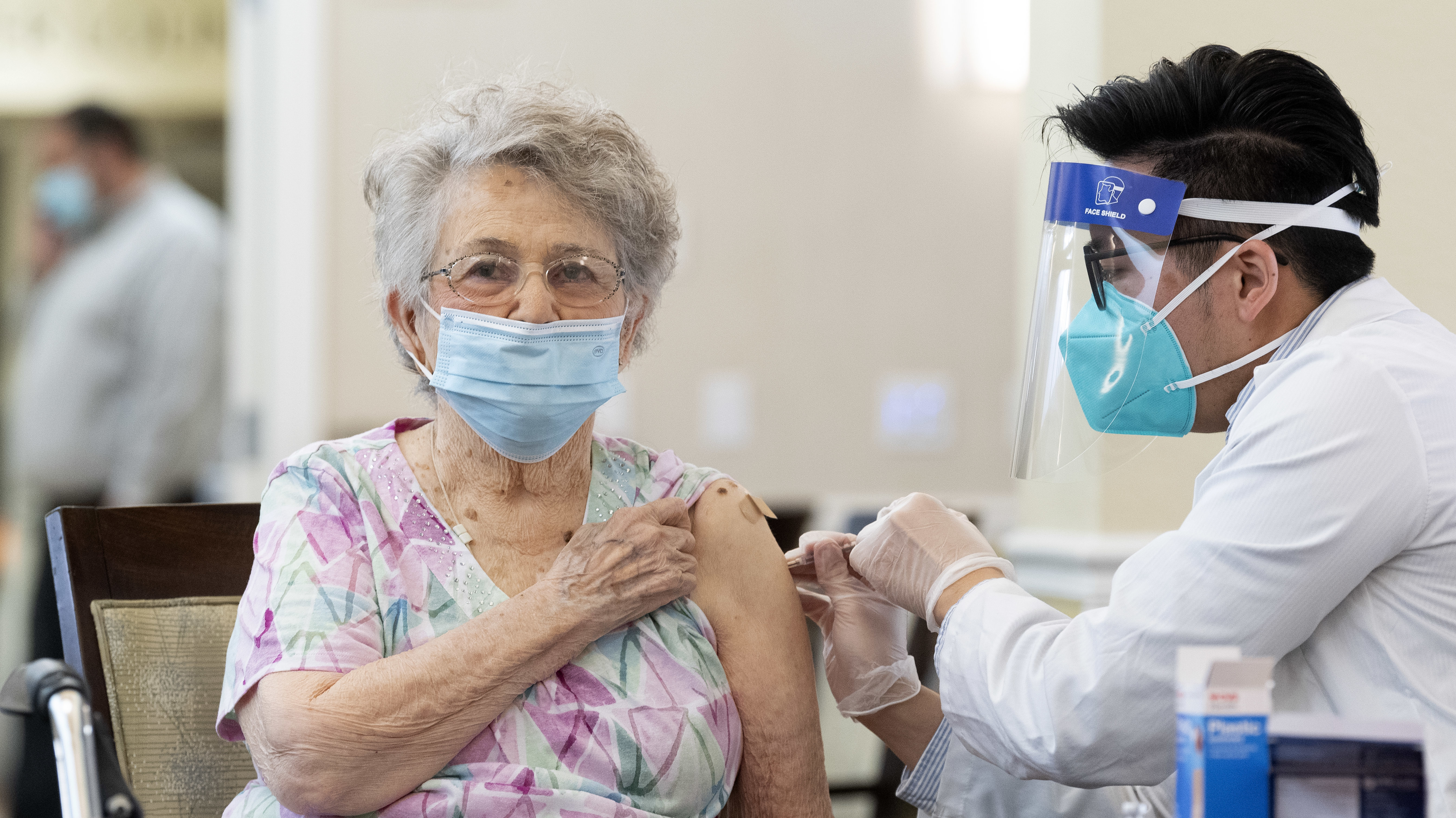 A CVS pharmacist gives the Pfizer/BioNTech COVID-19 vaccine to a resident at the Emerald Court senior living community in Anaheim, Calif., in January. Federal health officials have revised advice on nursing home visitations for the first time since September.