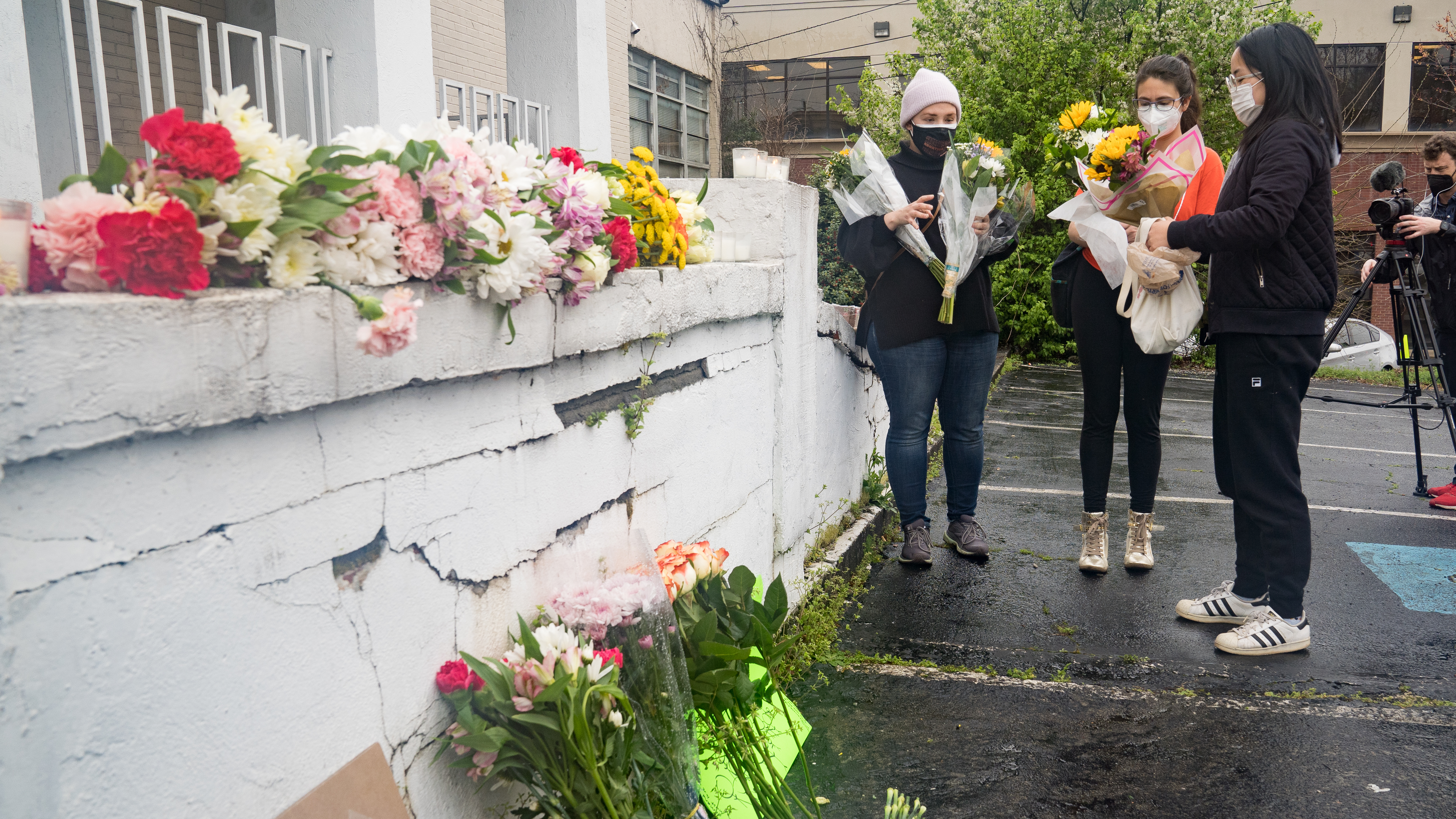 Mourners visit and leave flowers on Wednesday at the site of two shootings at spas across the street from one another in Atlanta.