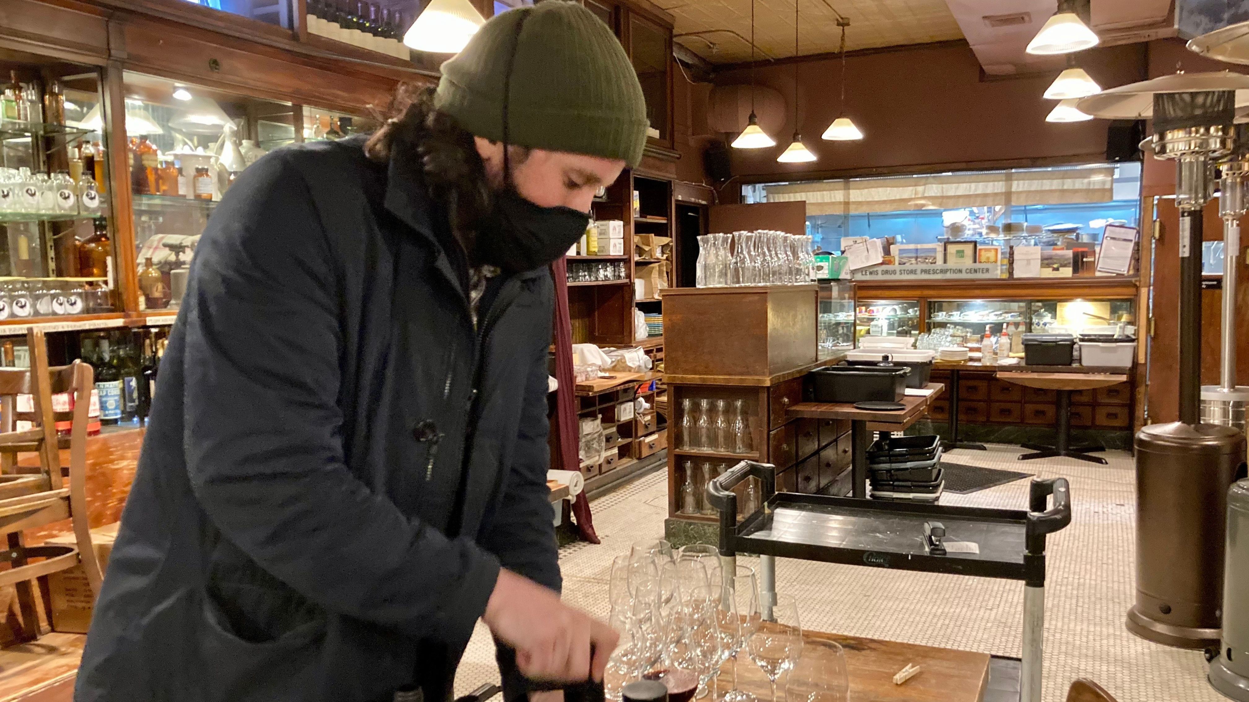 Michael Schall pours wine in Vini e Olli's dining room which has been turned into a storage space during the pandemic.
