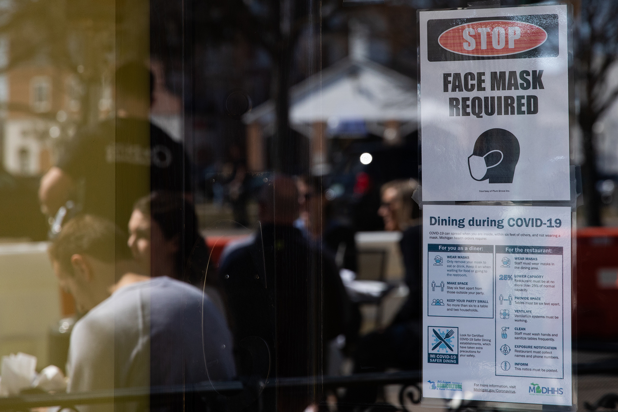 A sign requiring face masks and COVID-19 protocols is displayed at a restaurant in Plymouth, Mich., on March 21. Coronavirus cases in Michigan are skyrocketing after months of steep declines, one sign that a new surge may be starting. (Bloomberg via Getty Images)