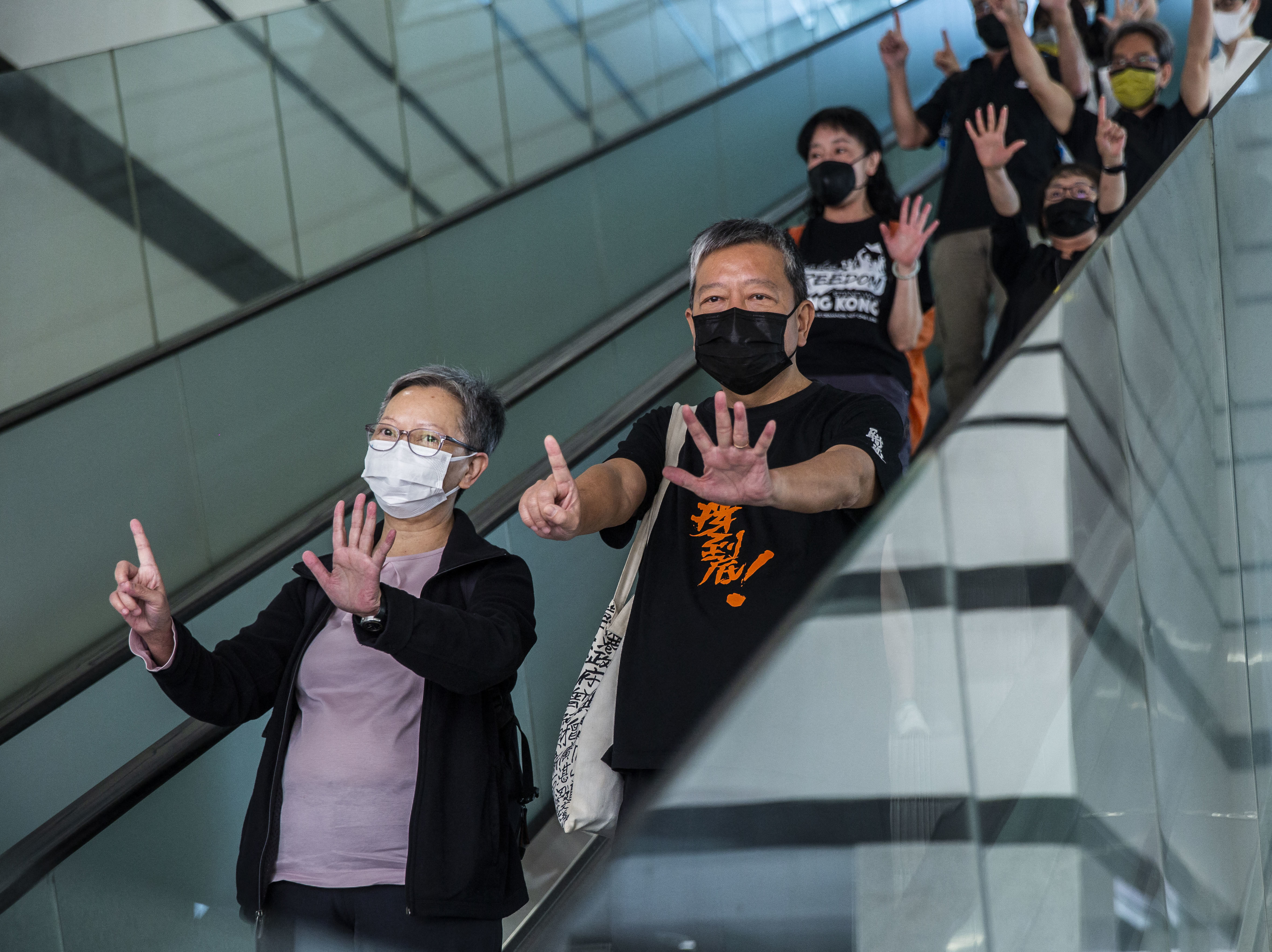 Former lawmaker Cyd Ho (left) and pro-democracy activist Lee Cheuk-yan (center) gesture a protest slogan, "Five demands, not one less," as they leave West Kowloon court in Hong Kong on Thursday after being found guilty of organizing an unauthorized assembly.