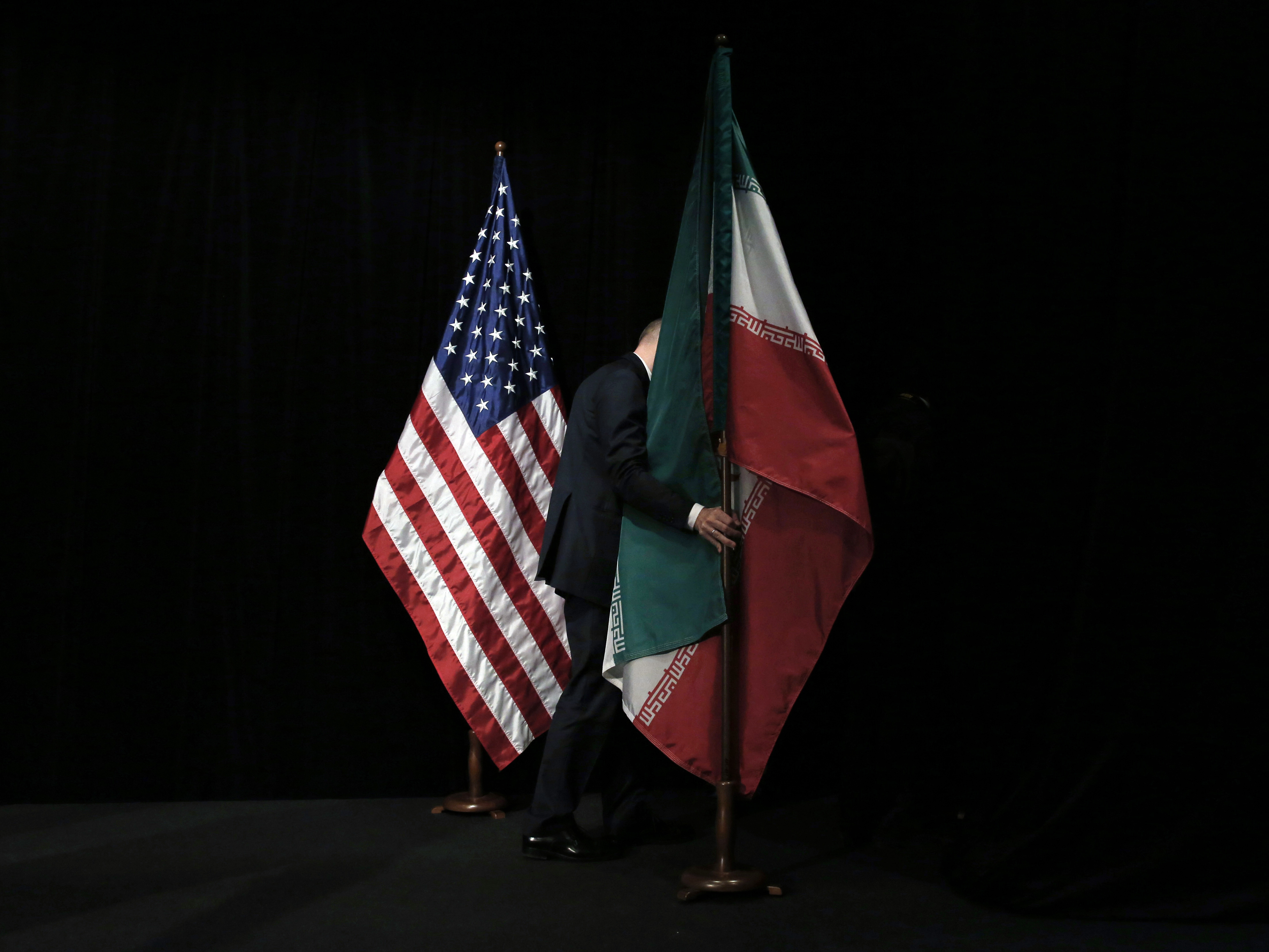 A staff person removes the Iranian flag from the stage after a group picture with representatives of the United States, Iran, China, Russia, Britain, Germany, France and the European Union during the Iran nuclear talks in July 2015 in Vienna. (Pool/AFP via Getty Images)