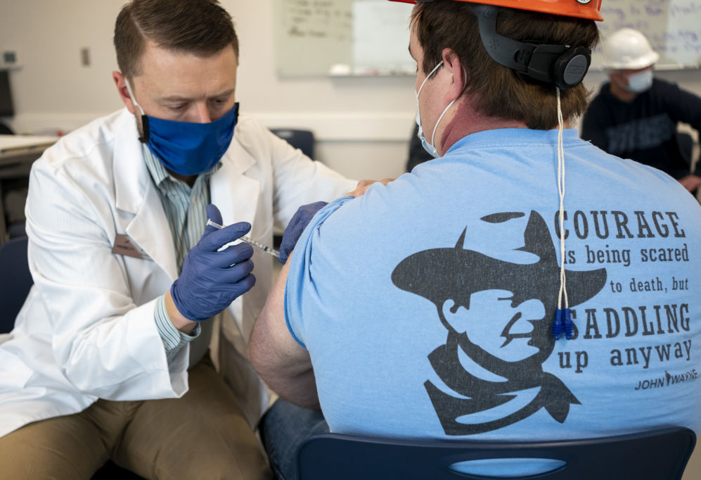 A pharmacist administers a dose of a COVID-19 vaccine to a worker at a processing plant in Arkansas City, Kan., on March 5. Researchers are concerned that vaccination rates in some rural communities may not keep up with urban rates. (Bloomberg via Getty Images)