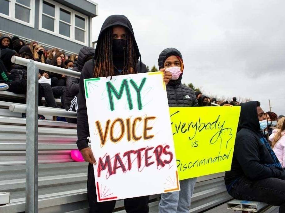 Students hold signs during a walkout at Tartan High School in Oakdale, Minn., where participants spoke, sang and did trauma-healing exercises together on the football field Monday. (MPR News)