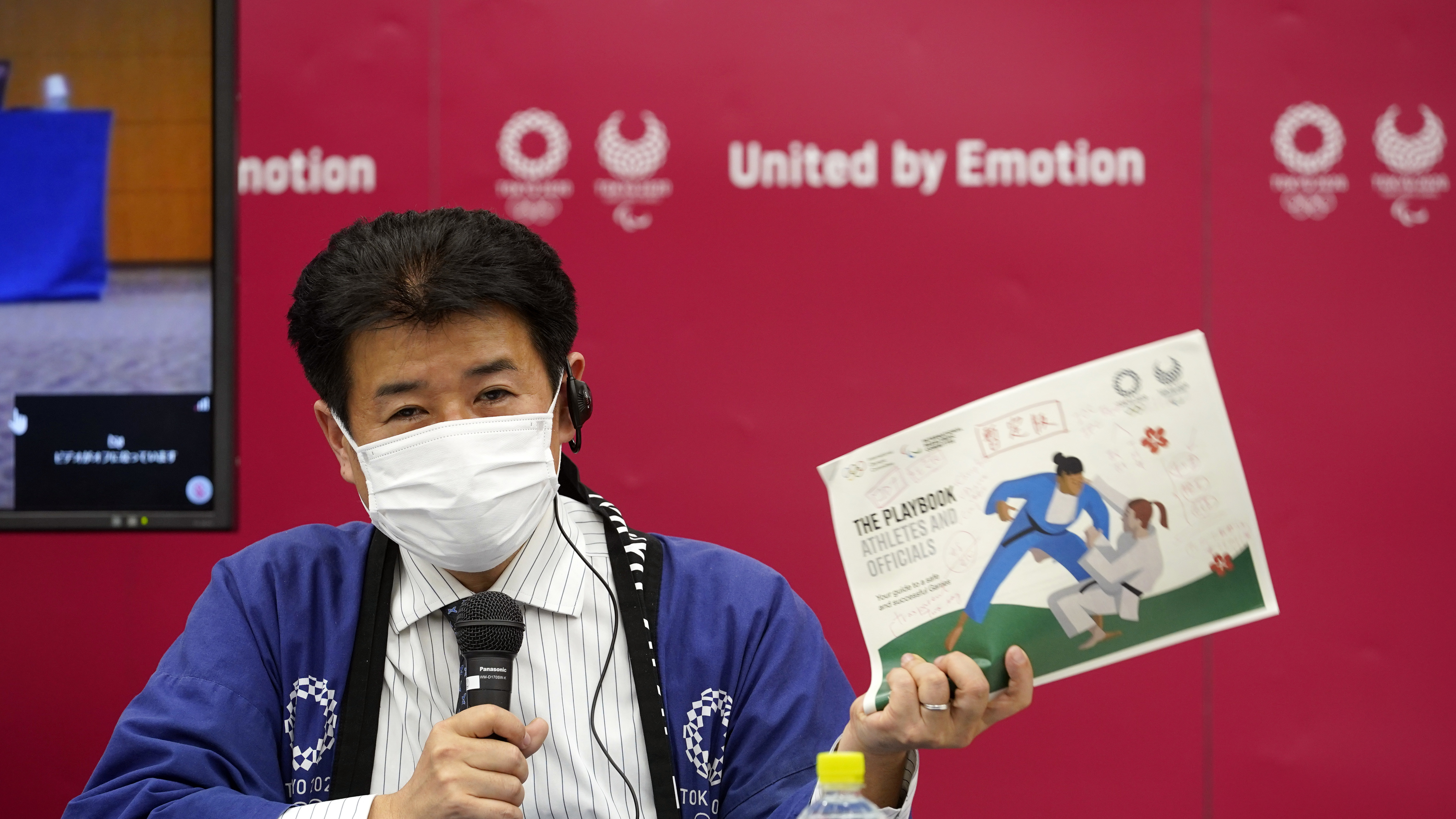 Tokyo 2020 Games Delivery Officer Hidemasa Nakamura holds a sample of an updated version of the Tokyo 2020 Playbook during a news briefing on Wednesday.