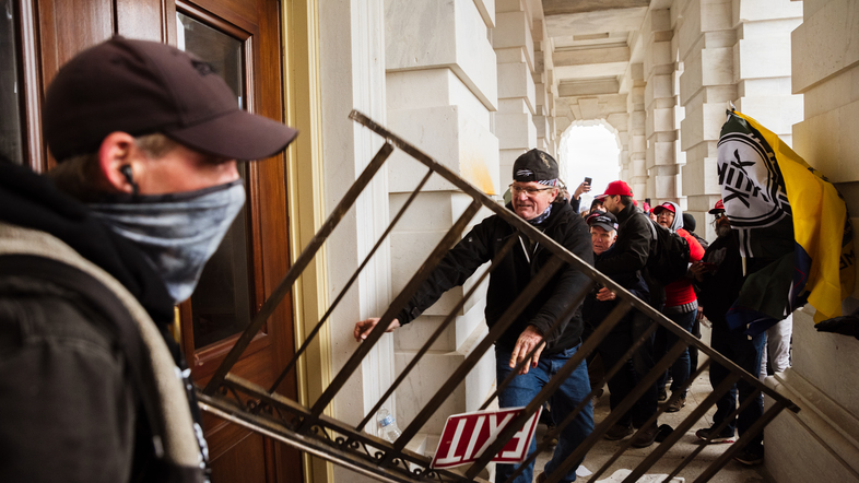 A member of a pro-Trump mob bashes an entrance of the Capitol building in an attempt to gain access on Jan. 6. The U.S. Capitol Police's inspector general has pointed to intelligence failures in the lead-up to the insurrection. (Jon Cherry/Getty Images)