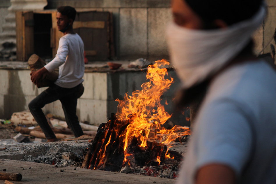 In New Delhi on Monday, family members cremate the body of a person who died after contracting COVID-19. (Mayank Makhija/NurPhoto via Getty Images)