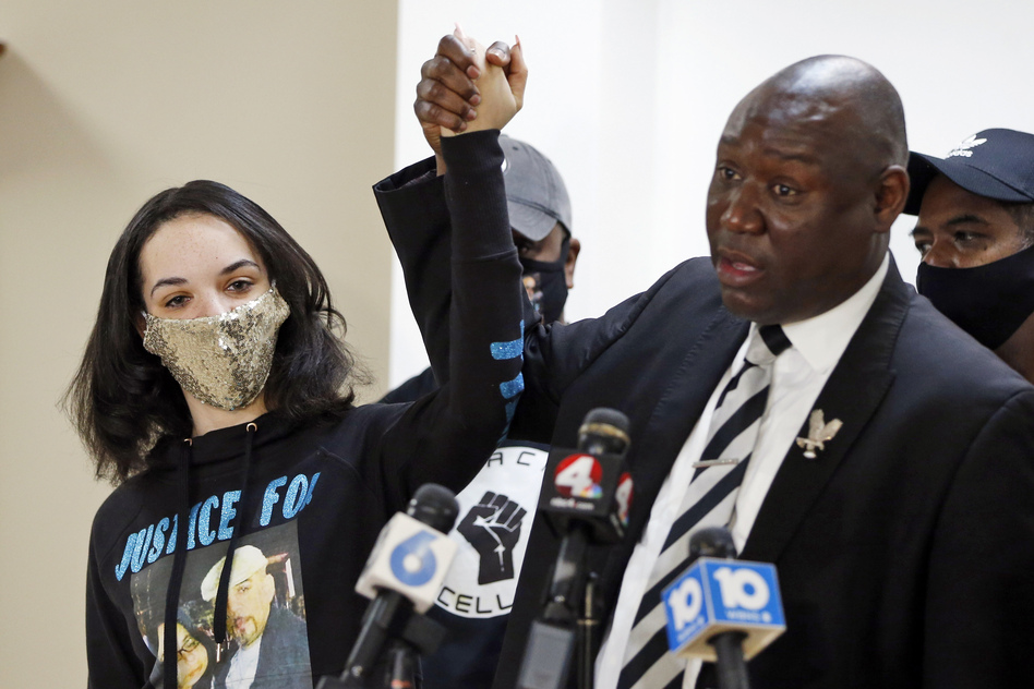 Karissa Hill, daughter of Andre Hill, raises hands with Benjamin Crump, the civil rights attorney representing Hill's family, at a news conference in February after former Columbus police officer Adam Coy was charged with murder in Hill's death.