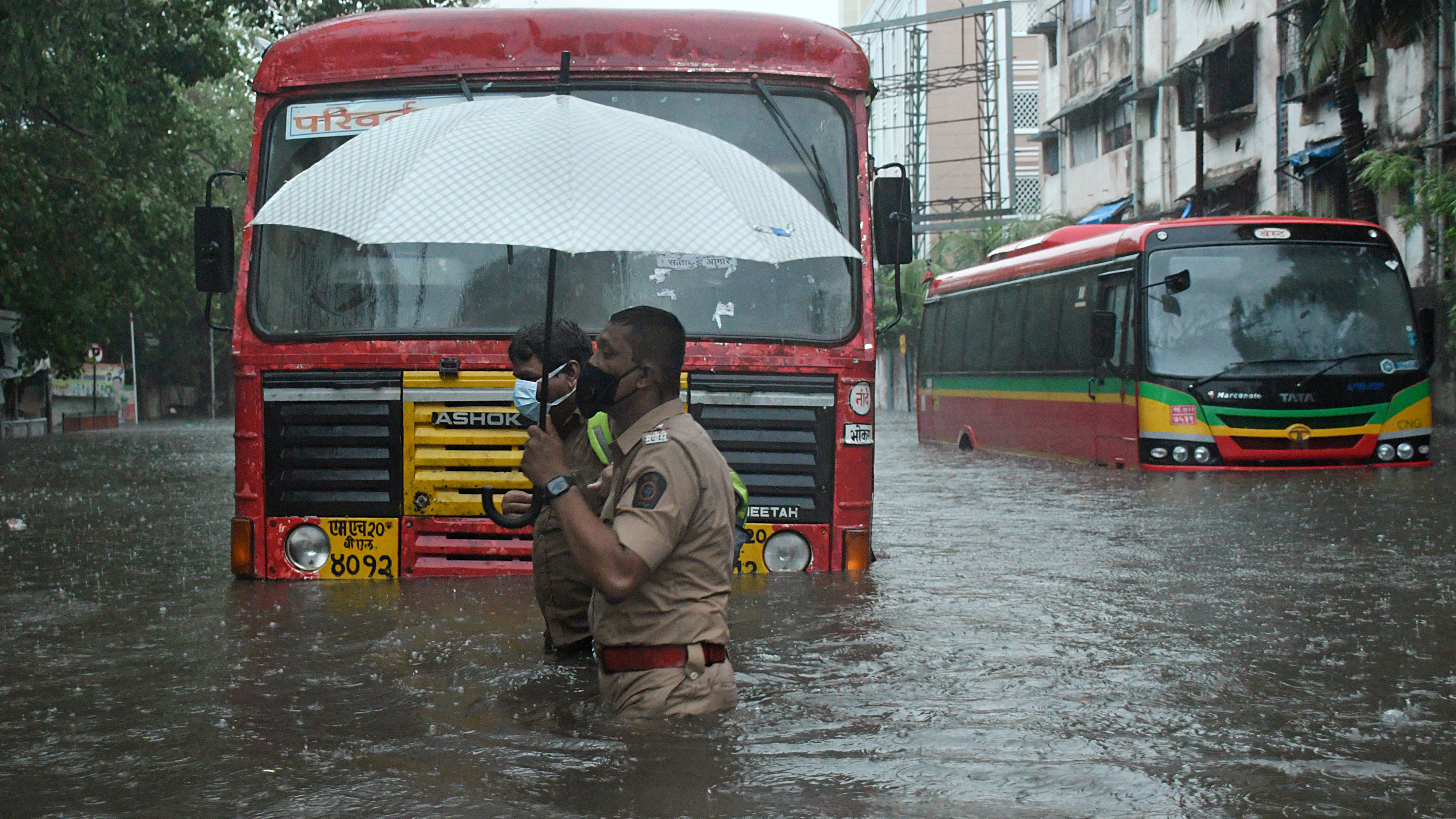 A policeman helps a public transport driver to cross a flooded street due to heavy rain caused by cyclone Tauktae in Mumbai.