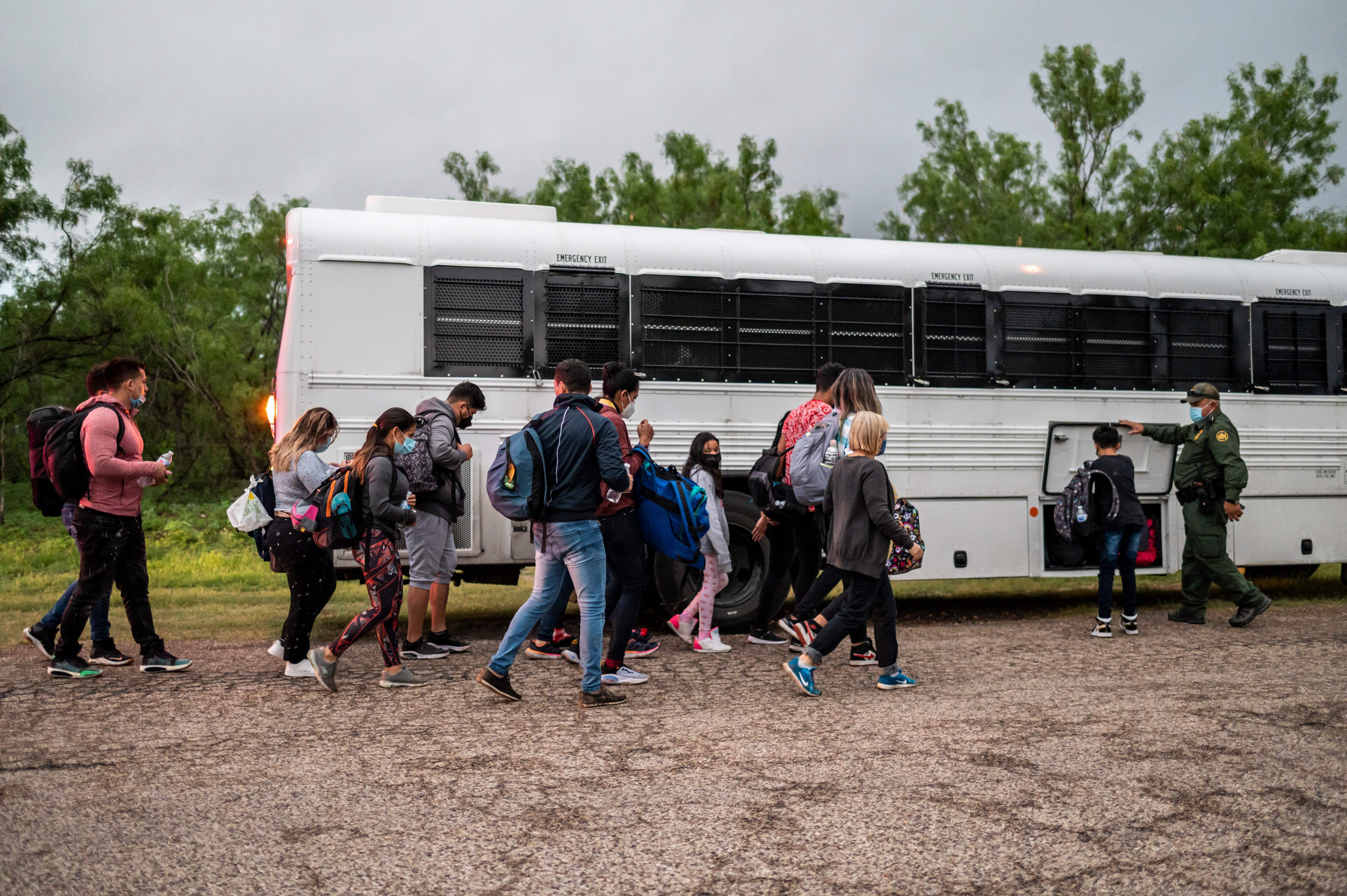 Migrants make their way toward a bus after being apprehended near the border between Mexico and the United States in Del Rio, Texas, on Sunday. (AFP via Getty Images)