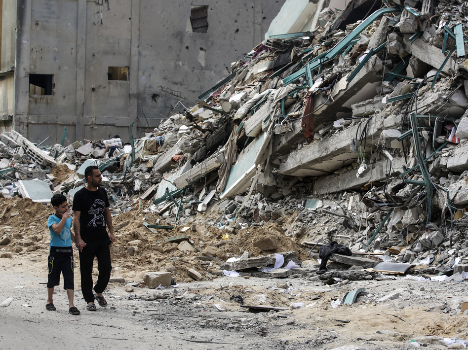 Palestinians walk past a destroyed tower after 11 days of deadly fighting that pounded Gaza and forced countless Israelis to seek shelter from rockets.