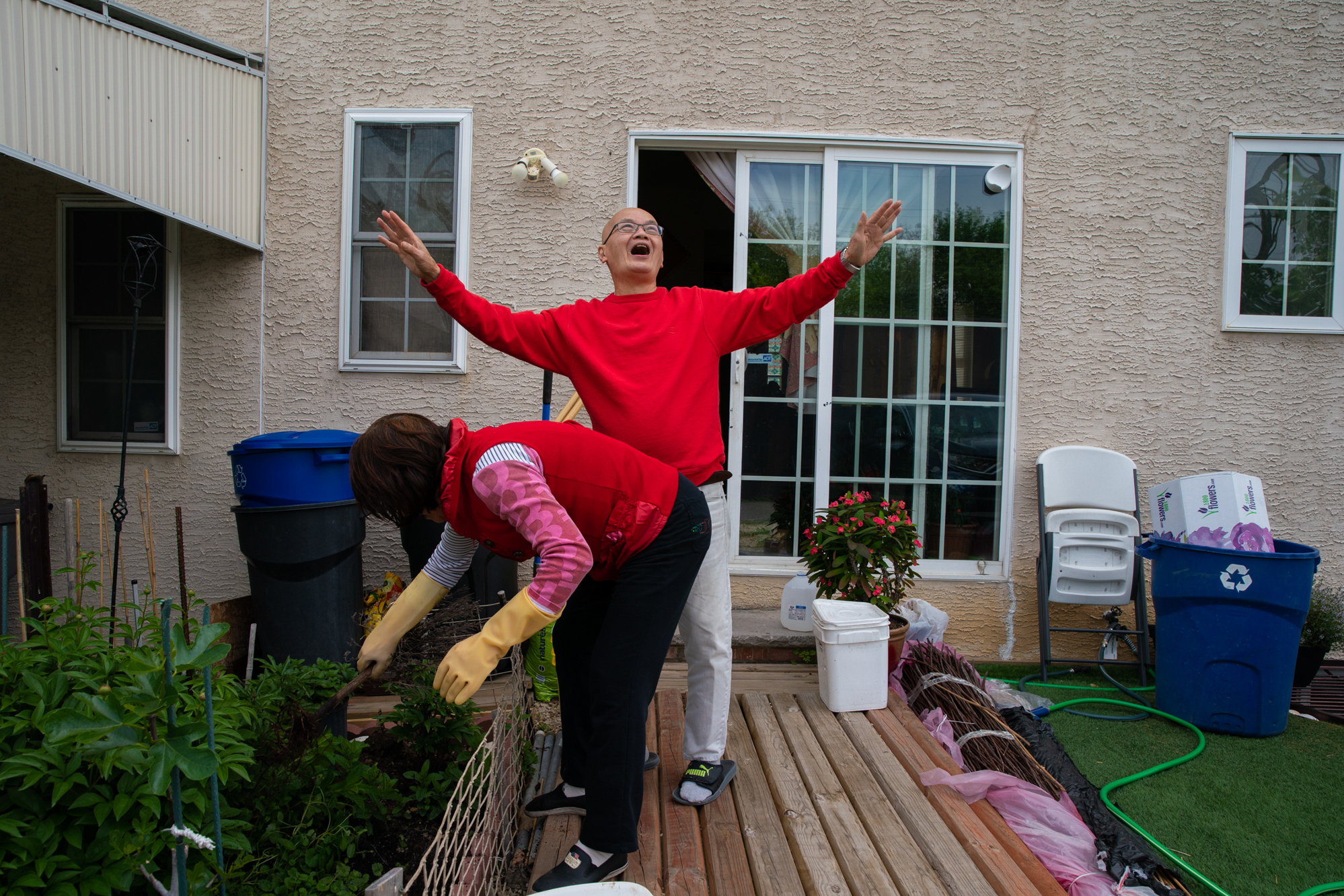 Photos: 2 Cantonese Women Share Their Immigrant Journey 16 The couple have a small garden in their backyard where they have planted their favorite flowers. Here, as Lai fertilizes the plants, Chan sings a love song for her.