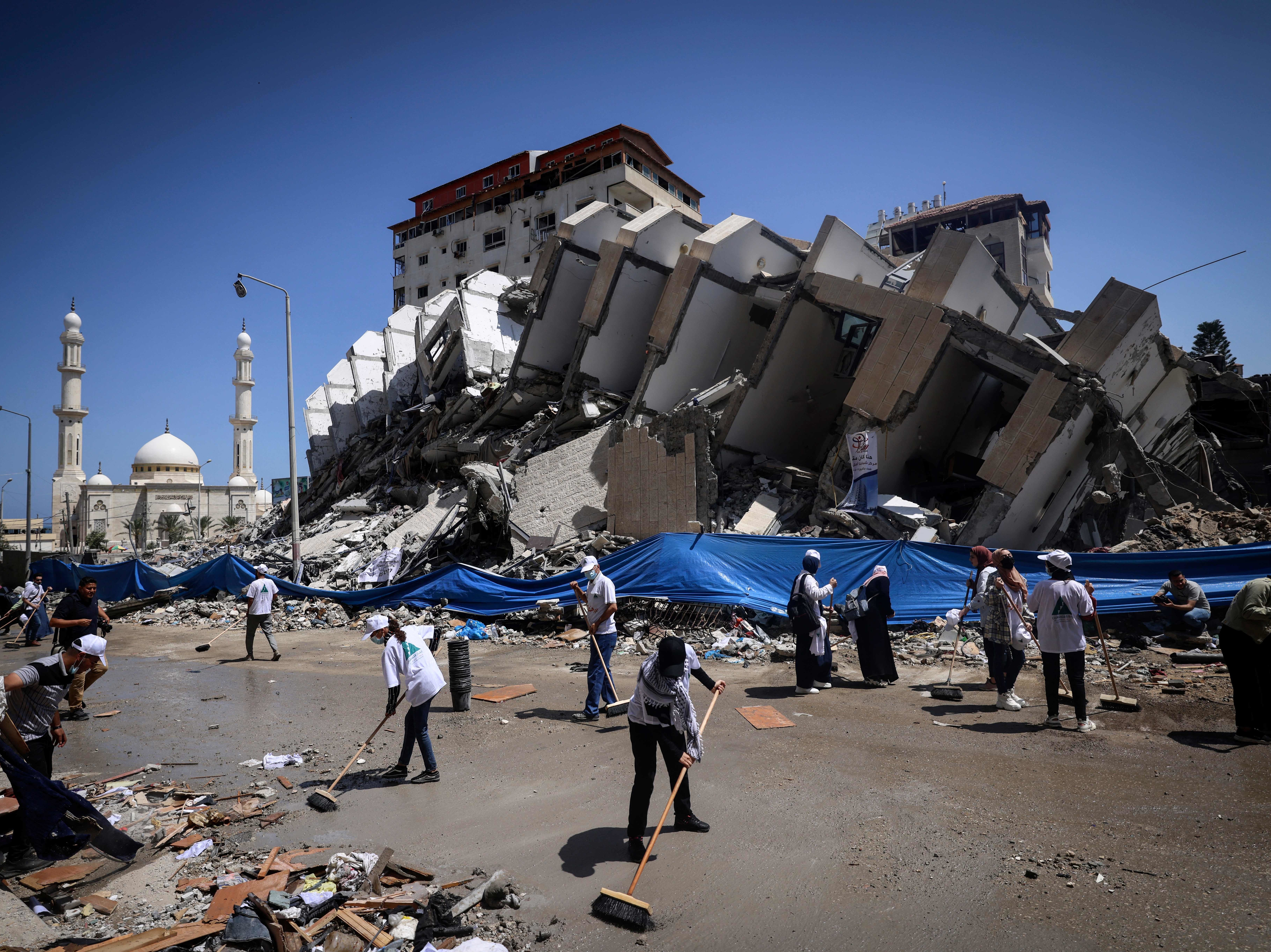 Palestinian volunteers and municipal workers clear the rubble of the Hanadi compound, recently destroyed by Israeli strikes, in Gaza City's Rimal district, on May 25, 2021. (AFP via Getty Images)