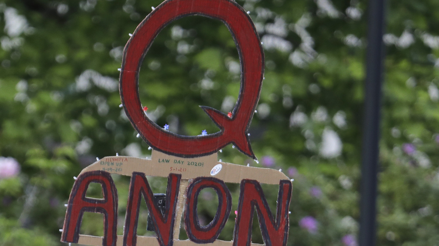                  A person carries a sign supporting QAnon during a May 2020 protest rally in Olympia, Wash.                                           