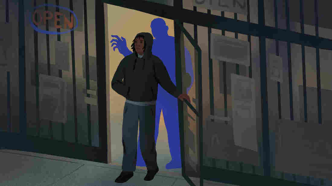 A teenager walks out of a store as a looming blue shape raises his hand behind him.