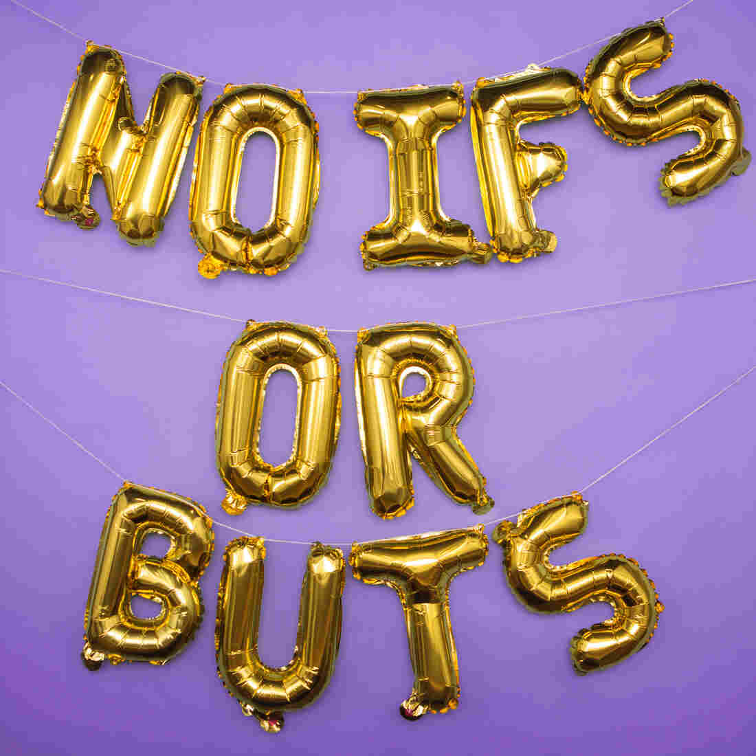 Gold foil balloon letters spelling out "no ifs or buts" are strung up in front of a purple backdrop.