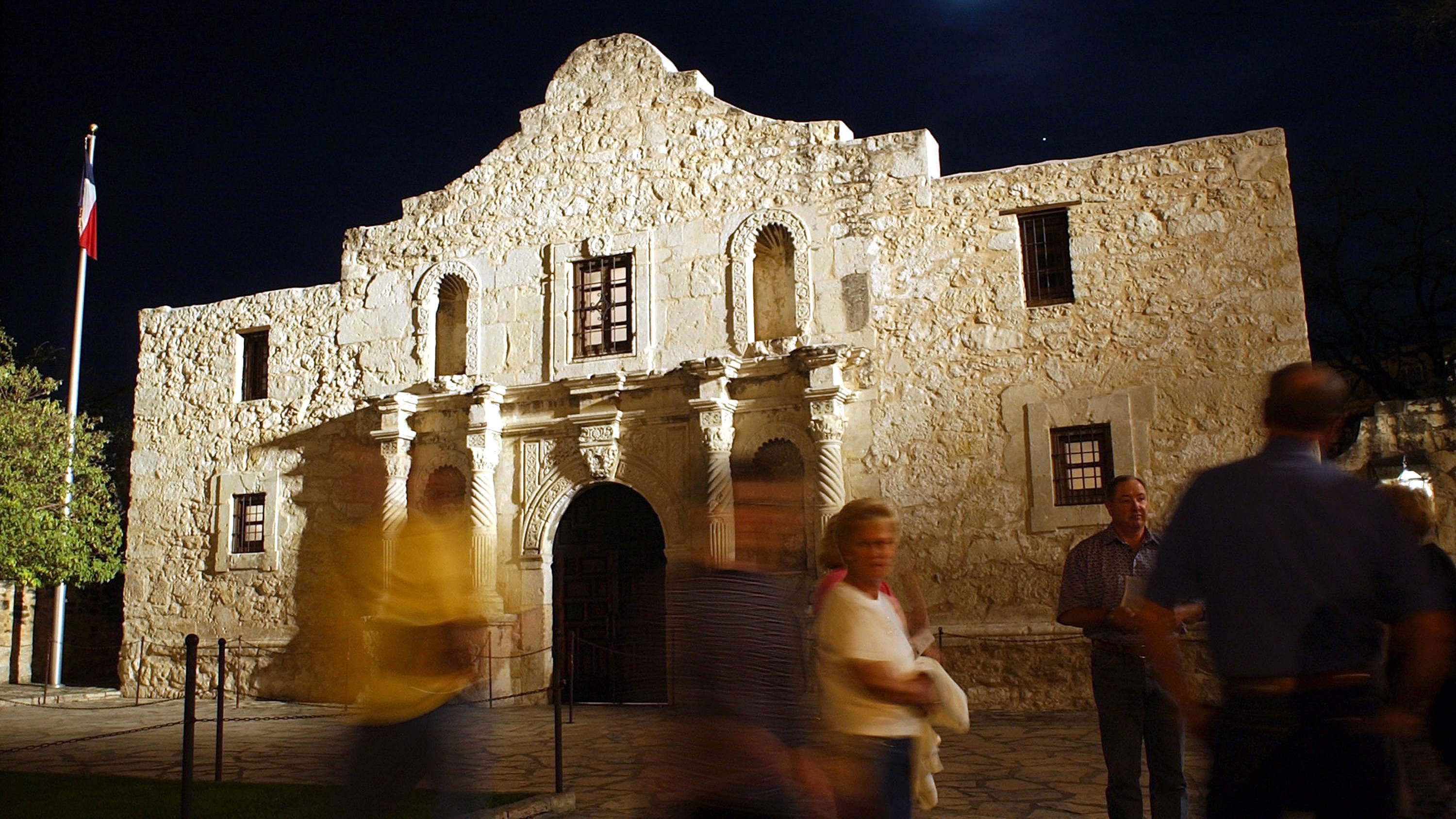 Visitors walk around the outside of the Alamo in San Antonio.