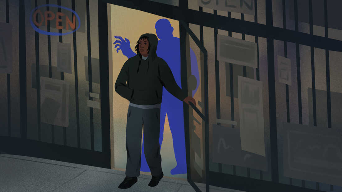 A teenager walks out of a store as a looming blue shape raises his hand behind him.