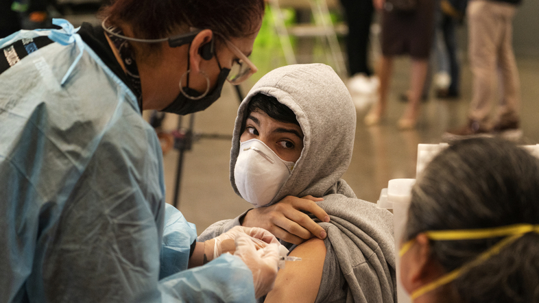 A student looks back at his mother, as he is vaccinated at a school-based COVID-19 vaccination clinic for students 12 and older in San Pedro, Calif., last month. (Damian Dovarganes/AP)