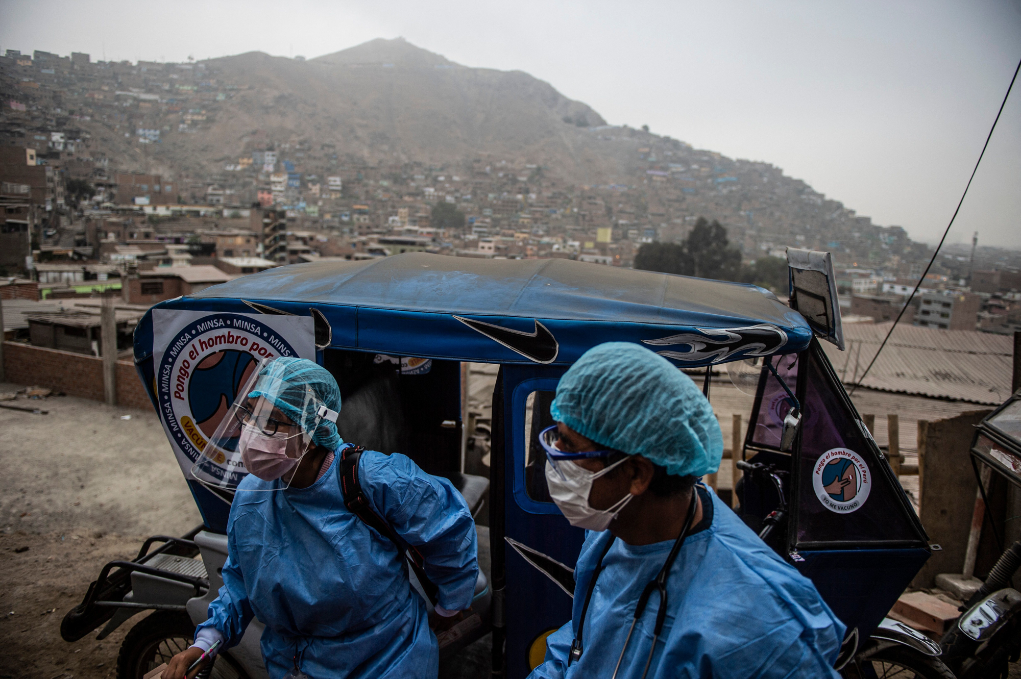 Health workers arrive in a tuk-tuk to administer doses of the Pfizer COVID-19 vaccine to elderly citizens in their homes in Lima, Peru, in April. (AFP via Getty Images)