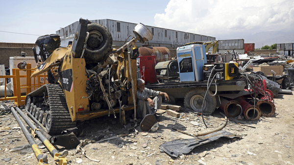 A man rests in the shade of destroyed machinery sold by the U.S. military to a scrapyard outside Bagram Air Base.