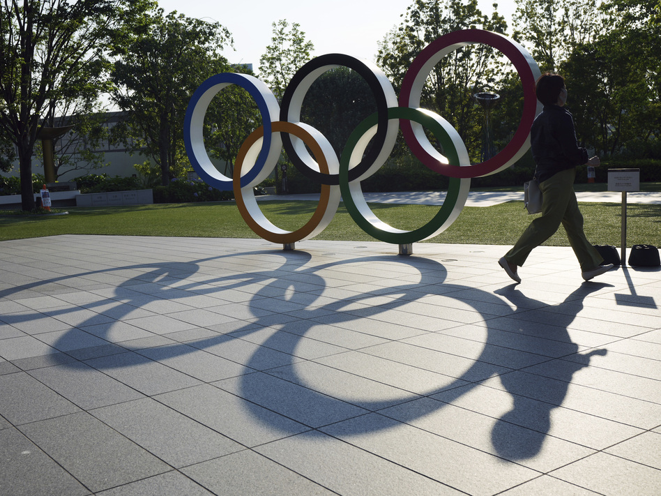 A woman passes the Olympic Rings near the National Stadium last month in Tokyo. There won't be any spectators at Olympic events in Japan's capital. (Eugene Hoshiko/AP)