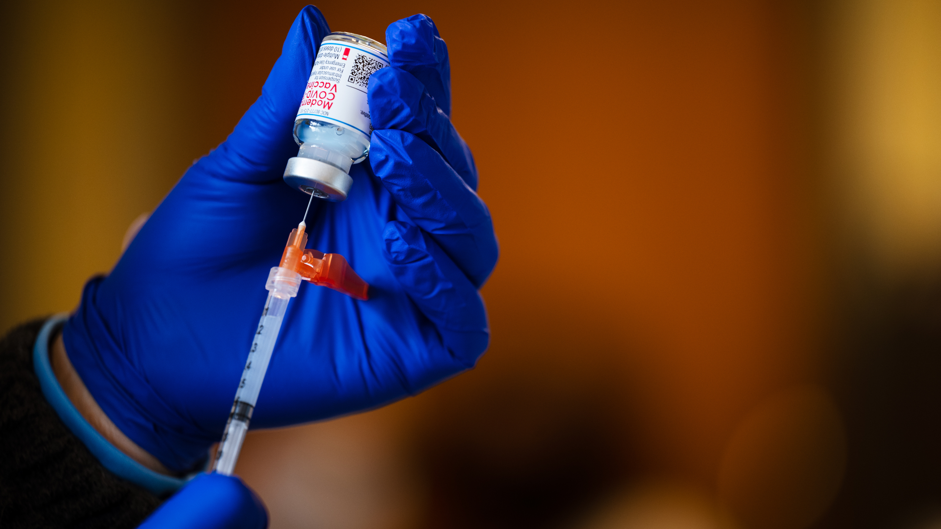 A technician fills a syringe from a vial of the Moderna COVID-19 vaccine earlier this year.