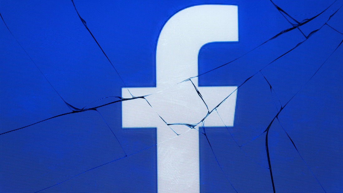 The logo of the social network Facebook appears on a broken screen of a mobile phone.