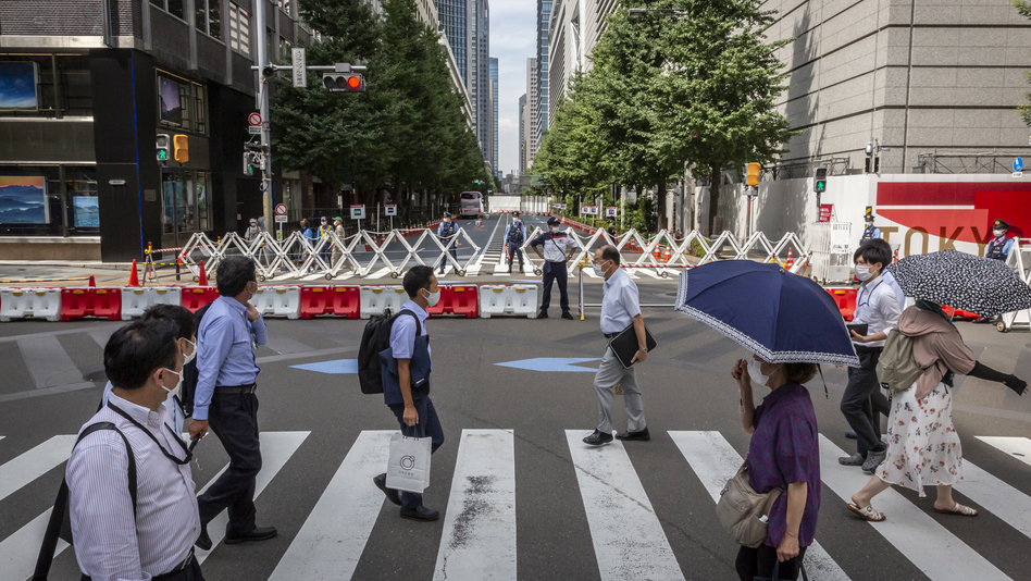 Tokyo's government is reporting new daily coronavirus cases at a rate not seen in more than six months. Here, people cross a street next to the Tokyo International Forum.
