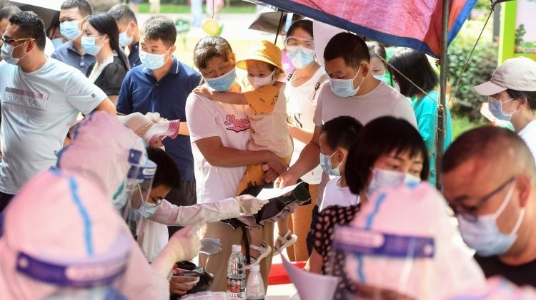 In Wuhan, China, residents wait in line for coronavirus testing on Tuesday. The city is testing its entire population for COVID-19 after the discovery of eight cases in the city.