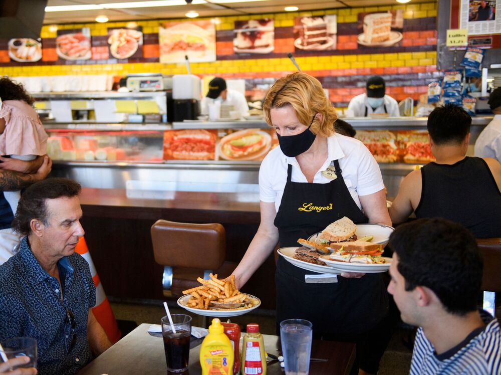 A server delivers food to customers dining at a restaurant in Los Angeles on Aug. 7. Restaurants are boosting pay to attract workers, and that could have an impact on already-high inflation. (AFP via Getty Images)