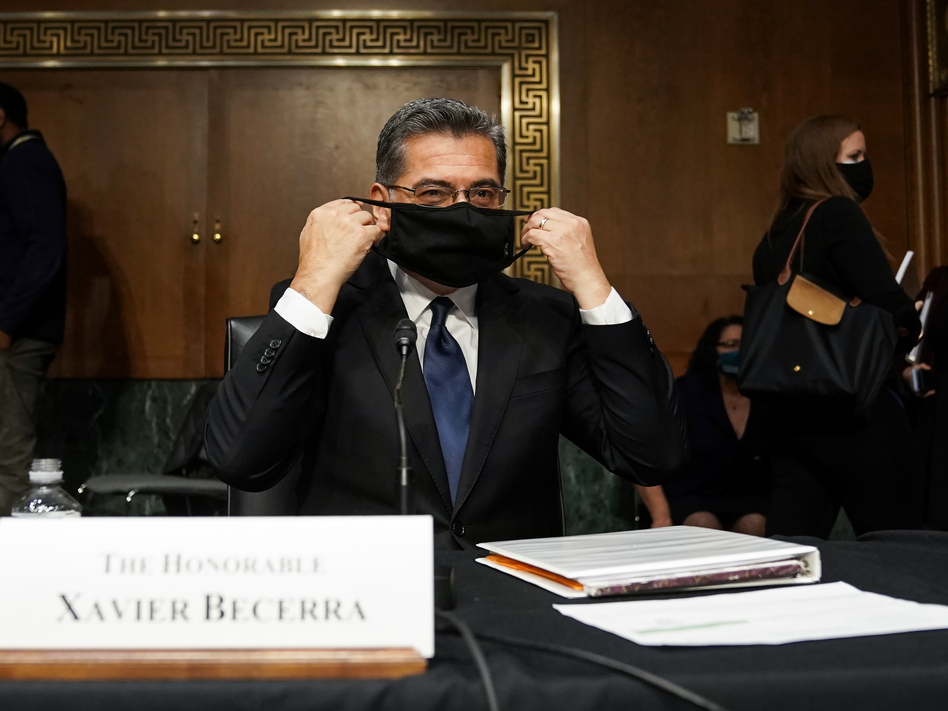 Xavier Becerra, then nominee for secretary of Health and Human Services, puts on his protective mask at his Senate Finance Committee confirmation hearing in February. (Greg Nash/The Hill/Bloomberg via Getty Images)