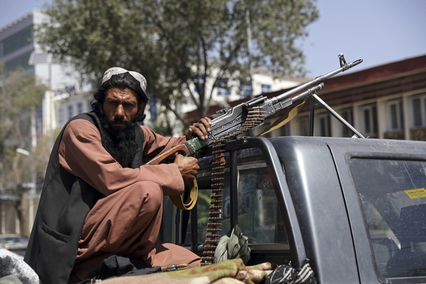 A Taliban fighter sits on the back of a vehicle with a machine gun in front of the main gate leading to the Afghan presidential palace, in Kabul, Afghanistan, Monday, Aug. 16, 2021. The U.S. military has taken over Afghanistan's airspace as it struggles to manage a chaotic evacuation after the Taliban rolled into the capital.