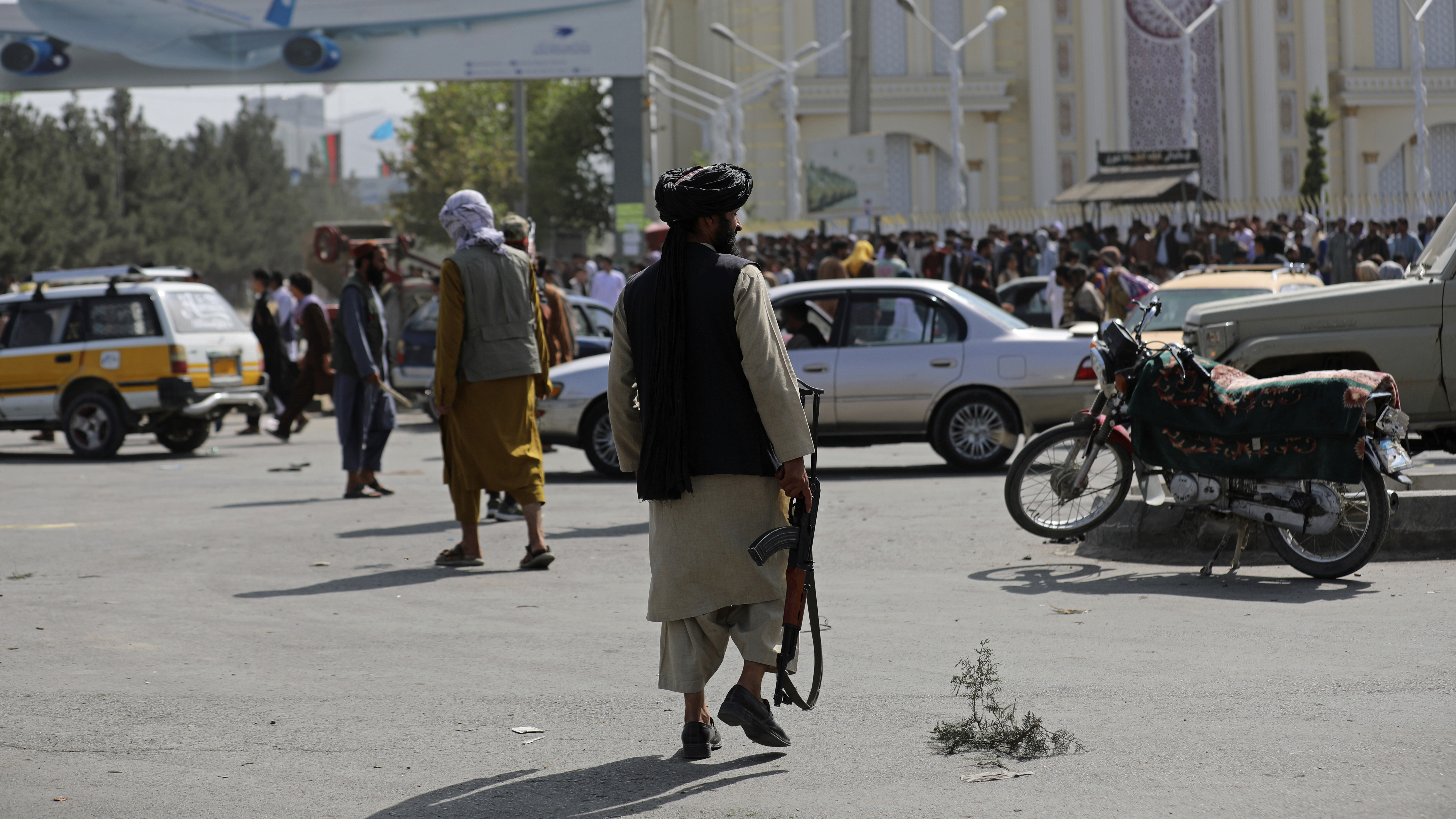 Taliban fighters stand guard in front of the Hamid Karzai International Airport in Kabul, Afghanistan, Monday. Thousands of people packed into the airport, rushing the tarmac and pushing onto planes in desperate attempts to flee the country after the Taliban took over.