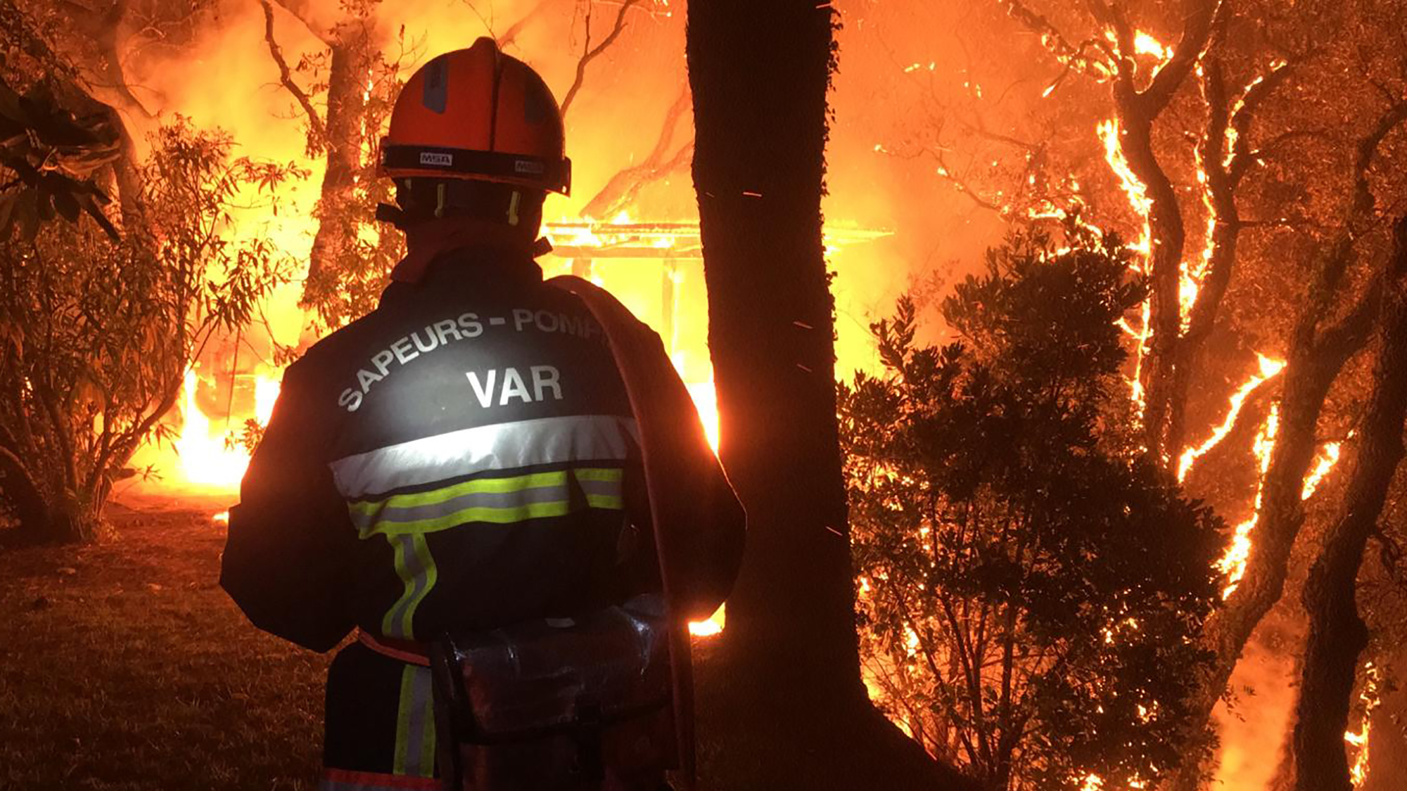 In this photo provided by the fire brigade of the Var region, a fireman battles with a fire near Toulon early Tuesday. Hundreds of firefighters on battled a fire racing through forests near the French Riviera that forced the evacuation of thousands of people from homes and vacation spots.