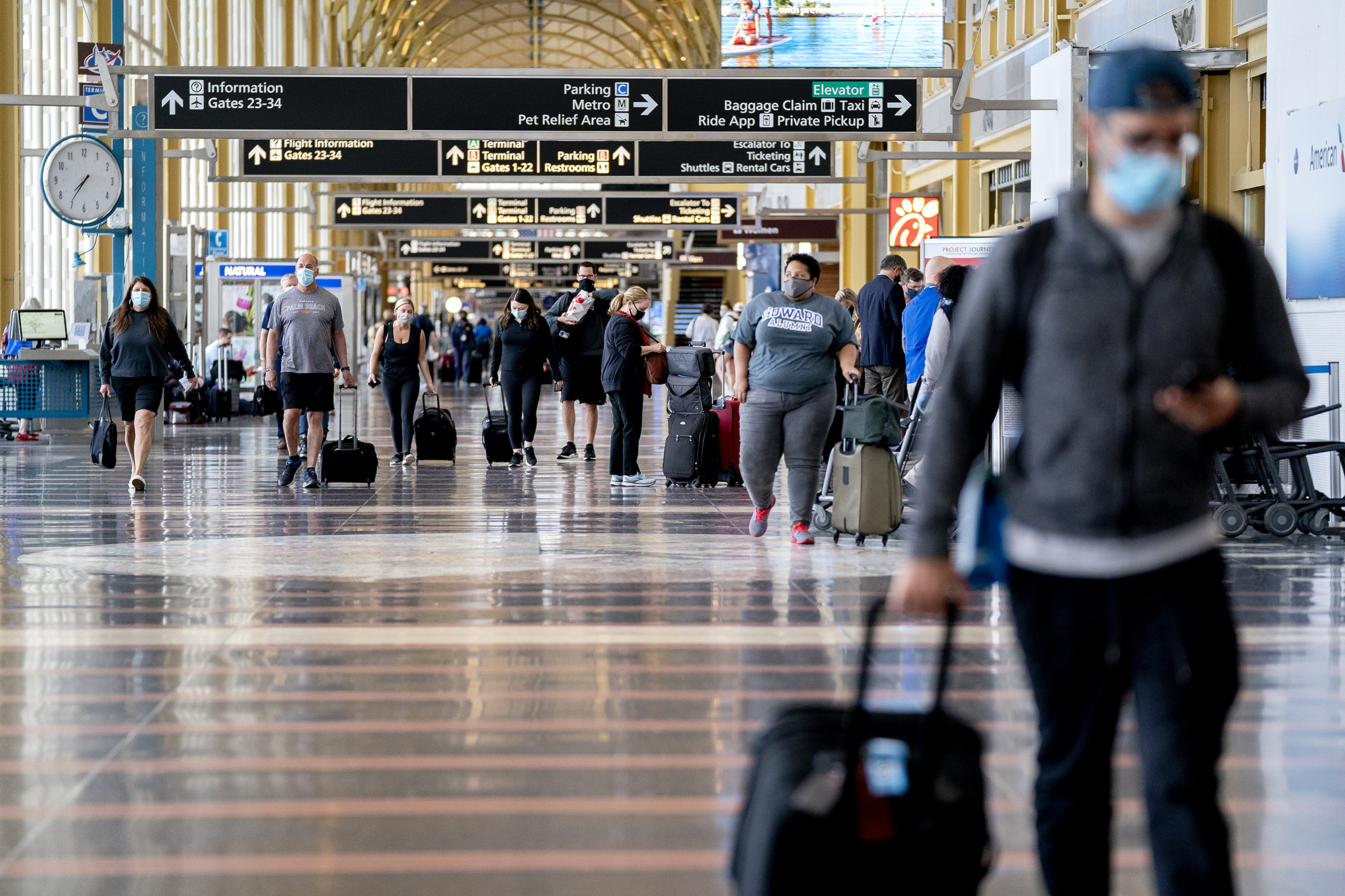 Mask-wearing travelers head through Reagan National Airport in Arlington, Va., in May. More than 70% of reports to the FAA of unruly passengers this year were related to people failing to comply with mask mandates and causing a disruption as a result. (Bloomberg via Getty Images)