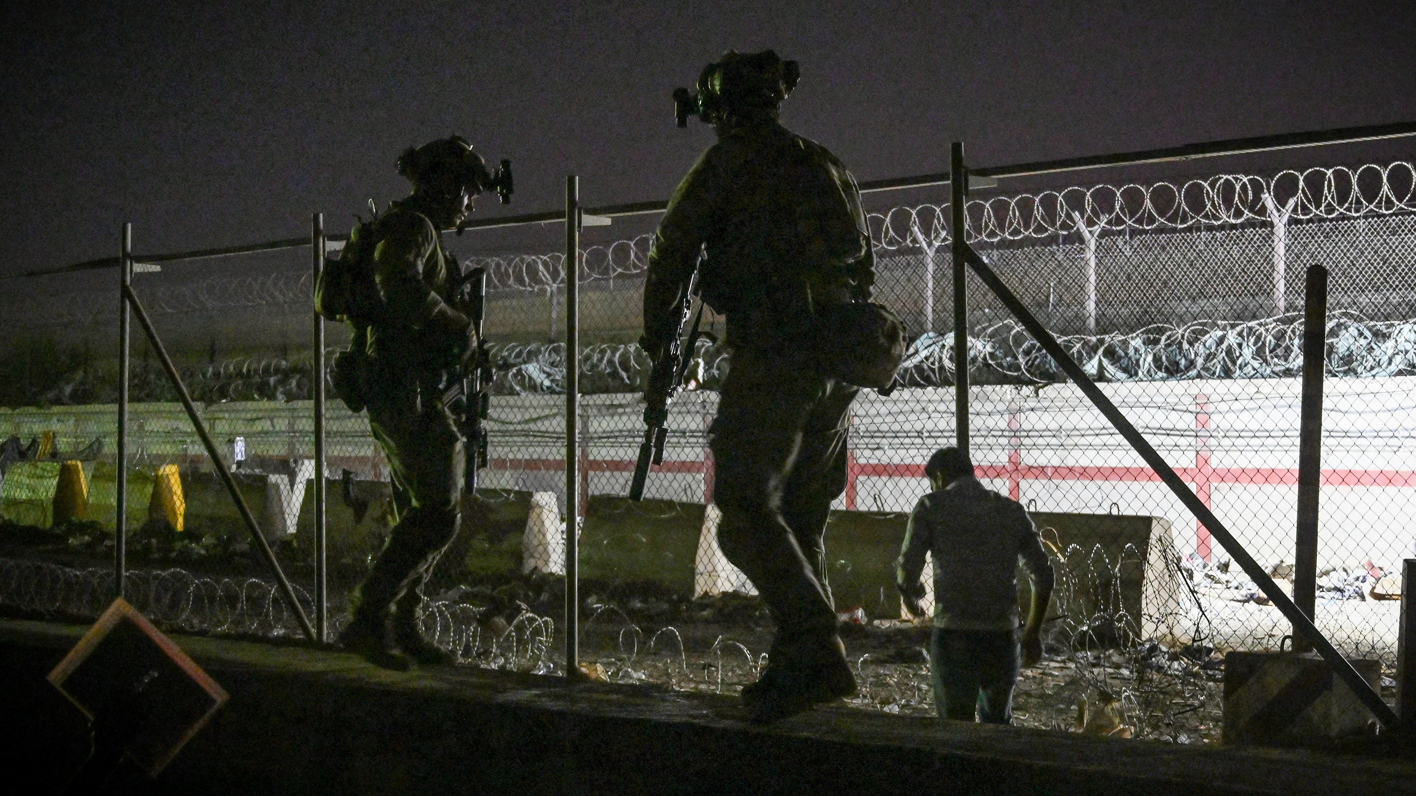 British and Canadian soldiers stand guard late Sunday near a canal as Afghans wait outside the foreign military-controlled part of the airport in Kabul, hoping to flee the country following the Taliban's military takeover of Afghanistan. (AFP via Getty Images)