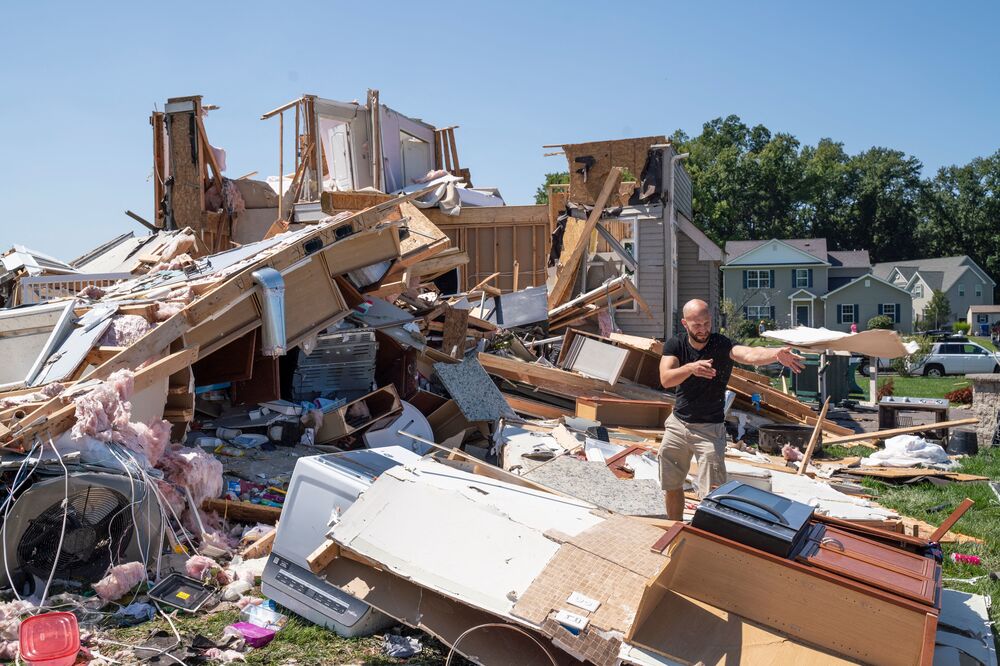 Sam Catrambone clears debris away from a friend's home that was damaged by a tornado in Mullica Hill, N.J., on Thursday after record-breaking rainfall brought by the remnants of Hurricane Ida that swept through the area. (AFP via Getty Images)