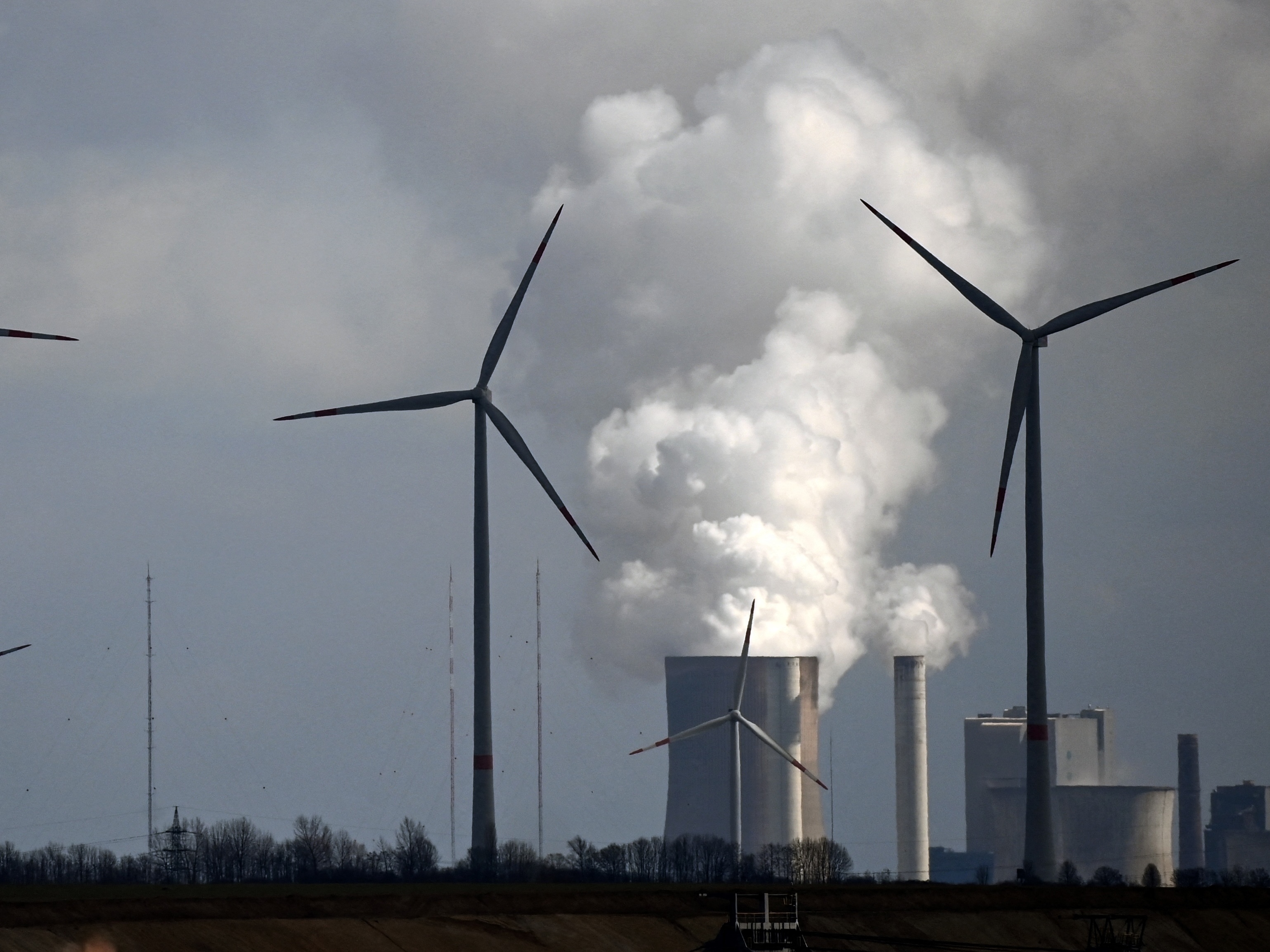 A new study finds that common climate change terms can be confusing to the public. That includes phrases that describe the transition from fossil fuels to cleaner sources of energy. Here, wind turbines operate near a coal-fired power plant in Germany. (AFP via Getty Images)