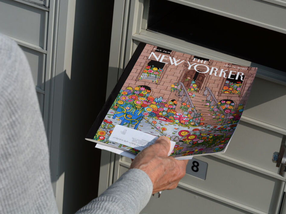A woman retrieves a copy of The New Yorker magazine from her mailbox in Santa Fe, N.M., in 2020.