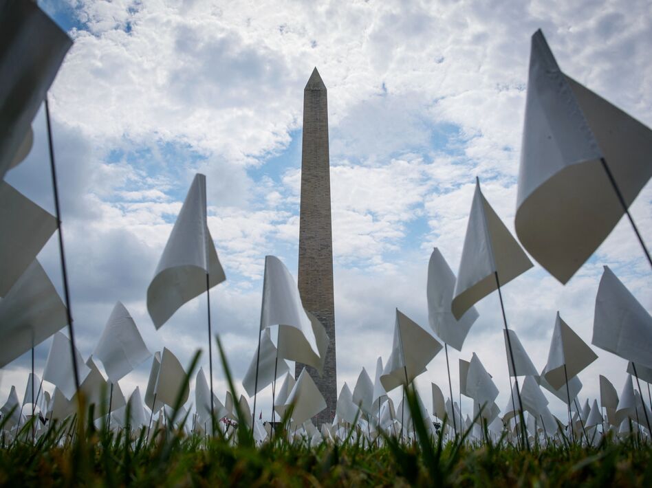 White flags stand near the Washington Monument on Tuesday during installation of a temporary art exhibit on the National Mall. More than 630,000 flags are part of artist Suzanne Brennan Firstenberg's <em>In America: Remember</em>, honoring Americans who have died of COVID-19. (Mandel Ngan/AFP via Getty Images)