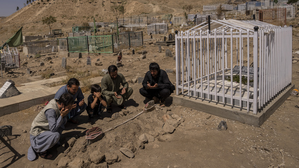 The Ahmadi family pray Monday at the cemetery next to family graves of family members killed by a U.S. drone strike in Kabul, Afghanistan.
