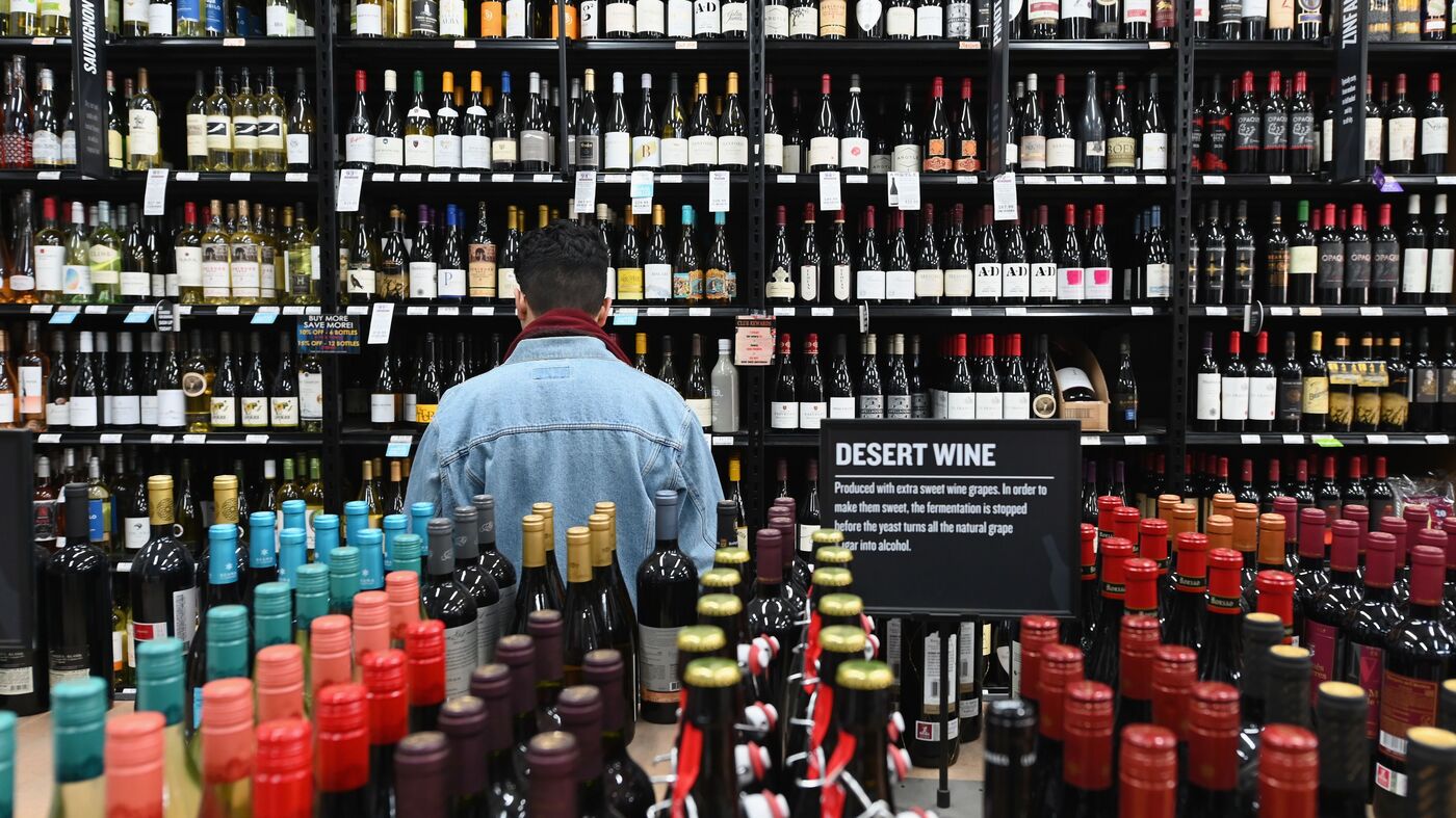                  A patron stands in front of a shelf of wine bottles at The Liquor Store.Com in Brooklyn, N.Y., last March.                           