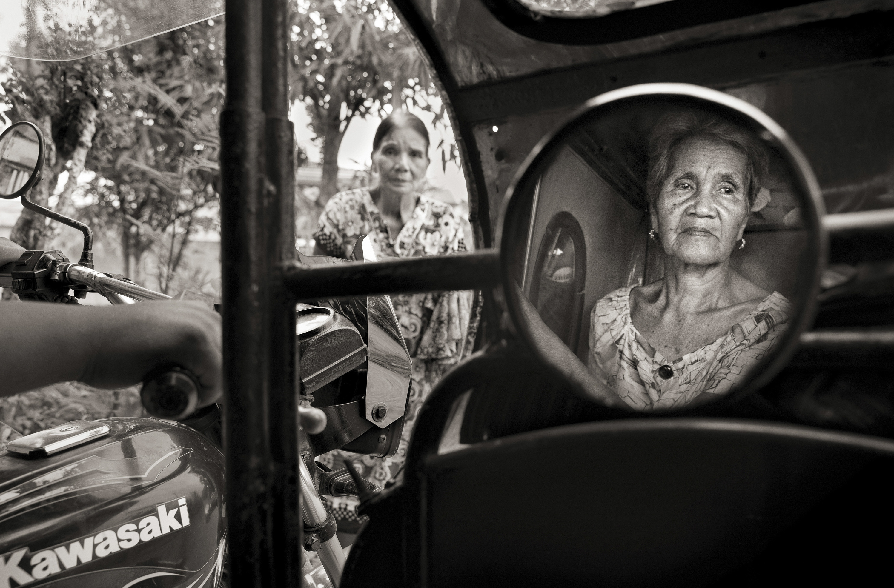 Isabelita Vinuya, 88, reflected in mirror, bids farewell to Perla Bulaon Balingit in the village of Mapaniqui in Pampanga. They are two of the last living &quot;comfort women&quot; of the Philippines. On Nov. 23, 1944, Vinuya, Balingit and some 100 other girls and women were taken to the Red House and systematically raped by the Japanese Imperial Army. (Cheryl Diaz Meyer for NPR)