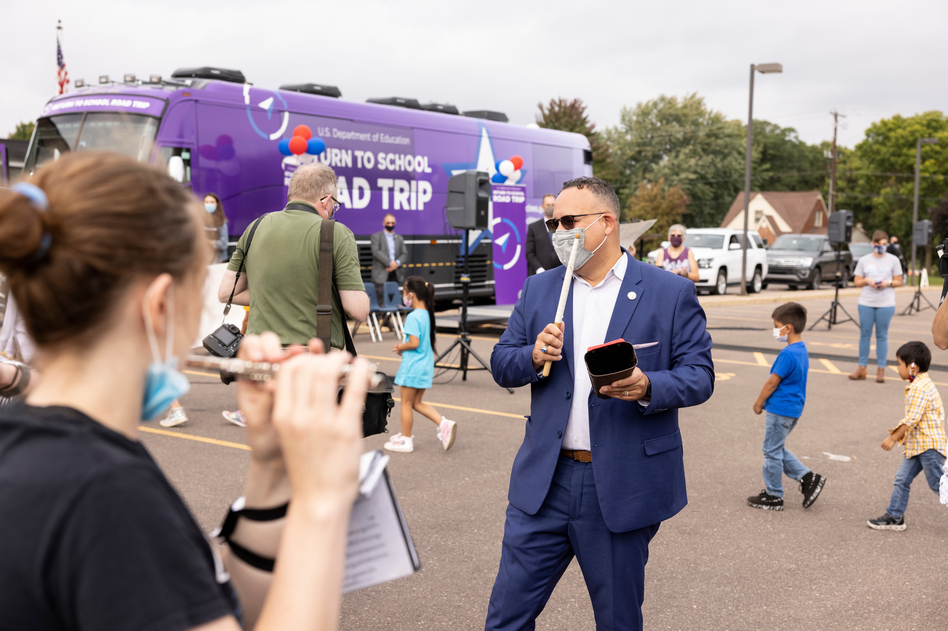 U.S. Education Secretary Miguel Cardona accompanies North High School's marching band on the cowbell during a Monday pep rally in Eau Claire, Wis.