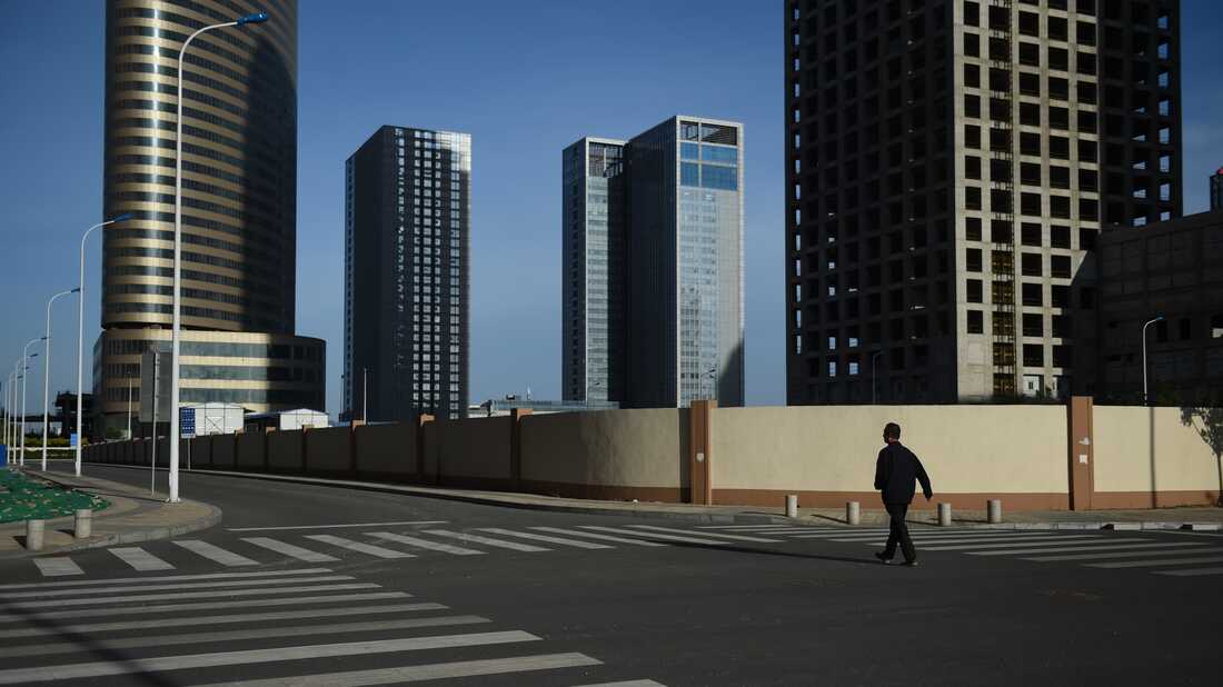 This photo taken on May 14, 2015 shows a man walking in an empty street in Conch Bay opposite the new Yujiapu financial district, in Tianjin, in northern China.