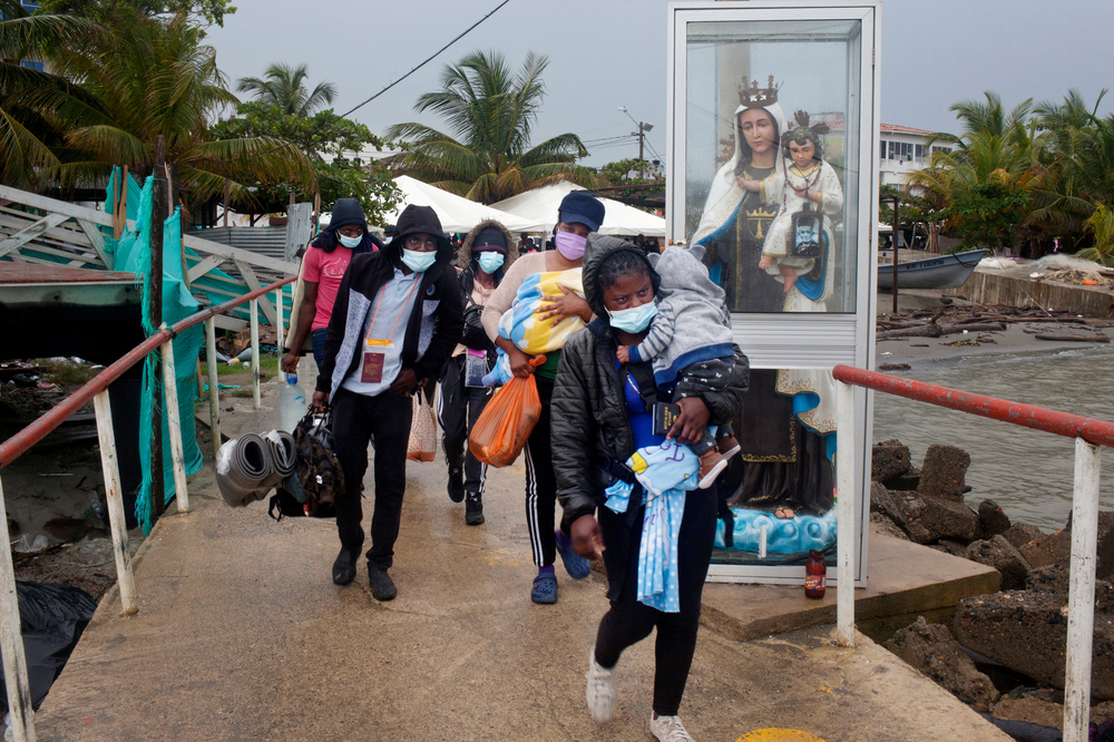 Haitian migrants in Necoclí, Colombia, walk toward boats that will take them to the town of Acandí, across the Gulf of Urabá. The boats can't keep up with the number of Haitians looking to travel from Colombia through the jungle to Panama to eventually reach the U.S. (Carlos Villalón for NPR)