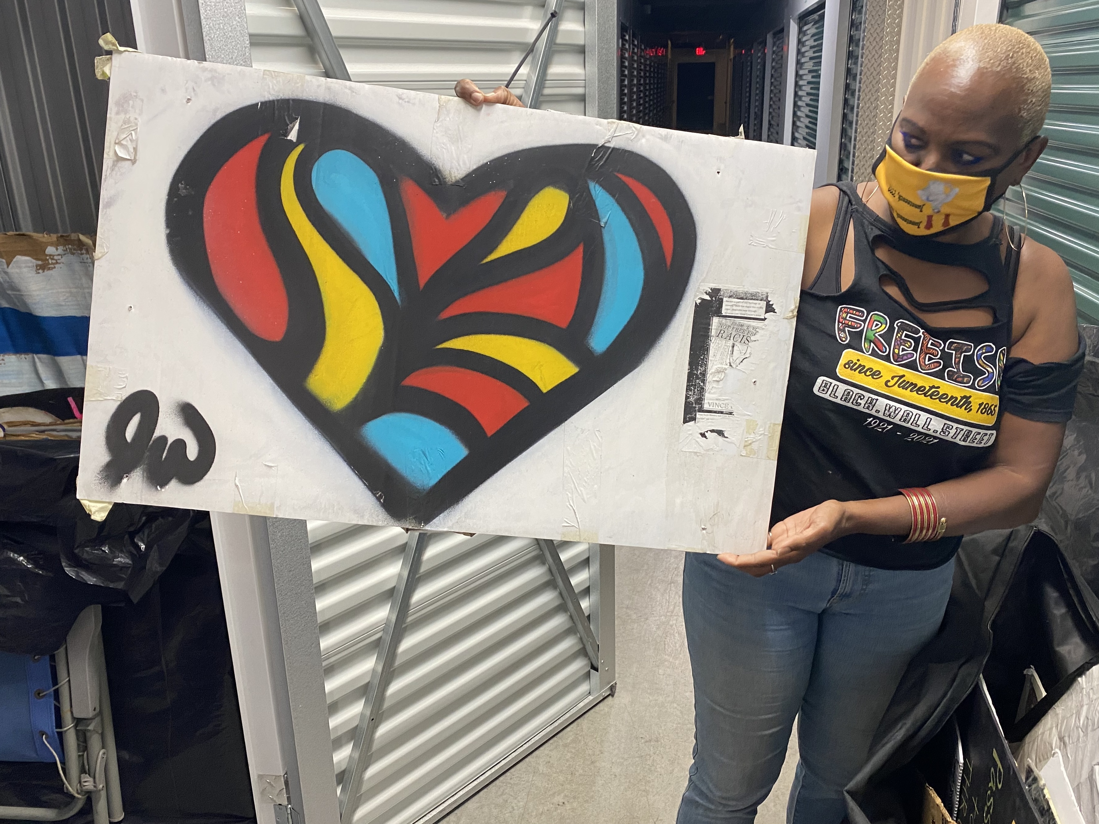 Nadine Seiler poses with a piece of artwork that was once displayed on the Black Lives Matter fence near the White House. Seiler is working to find new homes for the 700-plus artifacts left by protesters. (NPR)