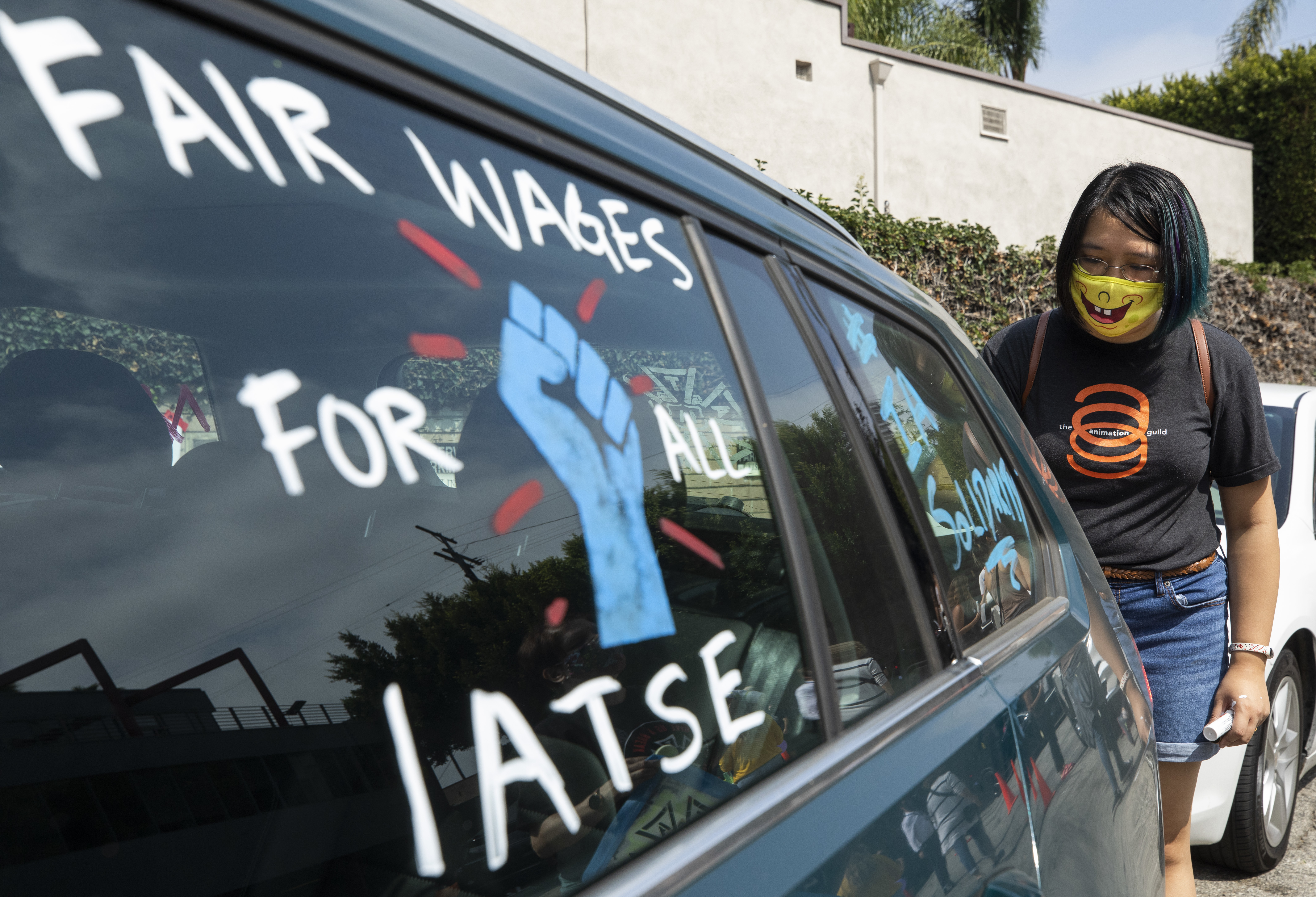 Crystal Kan, a storyboard artist, draws signs on cars of IATSE union members during a rally in Los Angeles in September. (Getty Images)